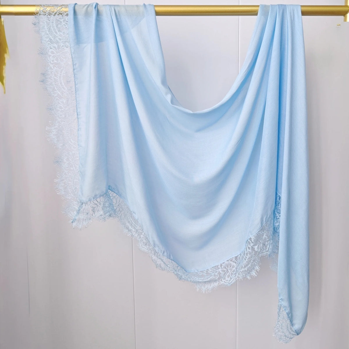 Hijab de gasa azul claro con estampado doble, drapeado sobre un percha dorada.