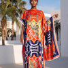 Eine Frau modelliert ein elegantes bedrucktes Seidenkaftan-Kleid mit leuchtenden orange-, blau- und gelben Mustern im Freien.