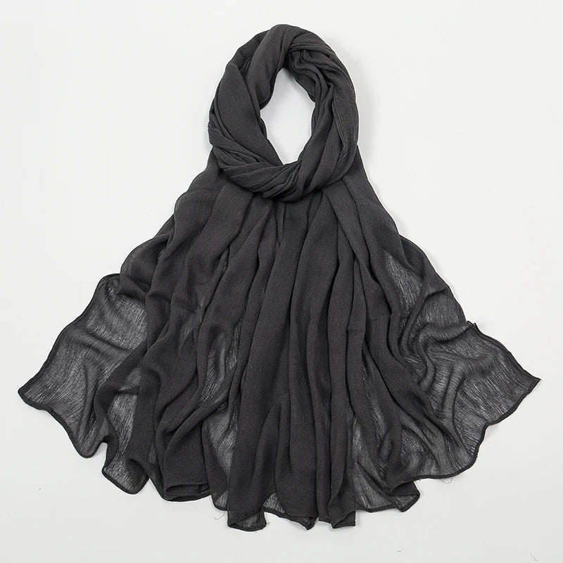 Écharpe châle crinklé en rayon gris foncé drapé sur fond blanc.
