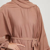 Eine Frau trägt eine mocha-farbene marokkanische Kaftan-Abaya mit langen Ärmeln und einem Gürteldetail.