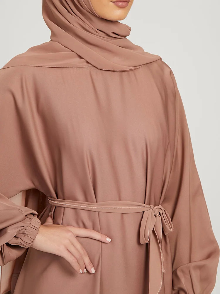 Eine Frau trägt eine mocha-farbene marokkanische Kaftan-Abaya mit langen Ärmeln und einem Gürteldetail.