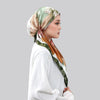 Une femme portant un foulard instant anti-slip en satin imprimé dans des tons de vert, brun et blanc.