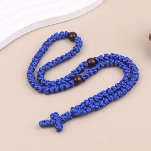 A blue handmade Orthodox rosary prayer rope necklace with wooden beads lying on a light background.