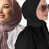 Una mujer vistiendo un hiyab malva y ropa negra con gafas de sol