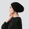Frau im Profil mit schwarzem Stretch-Jersey-Inner-Hijab-Cap und schwarzem Oberteil.