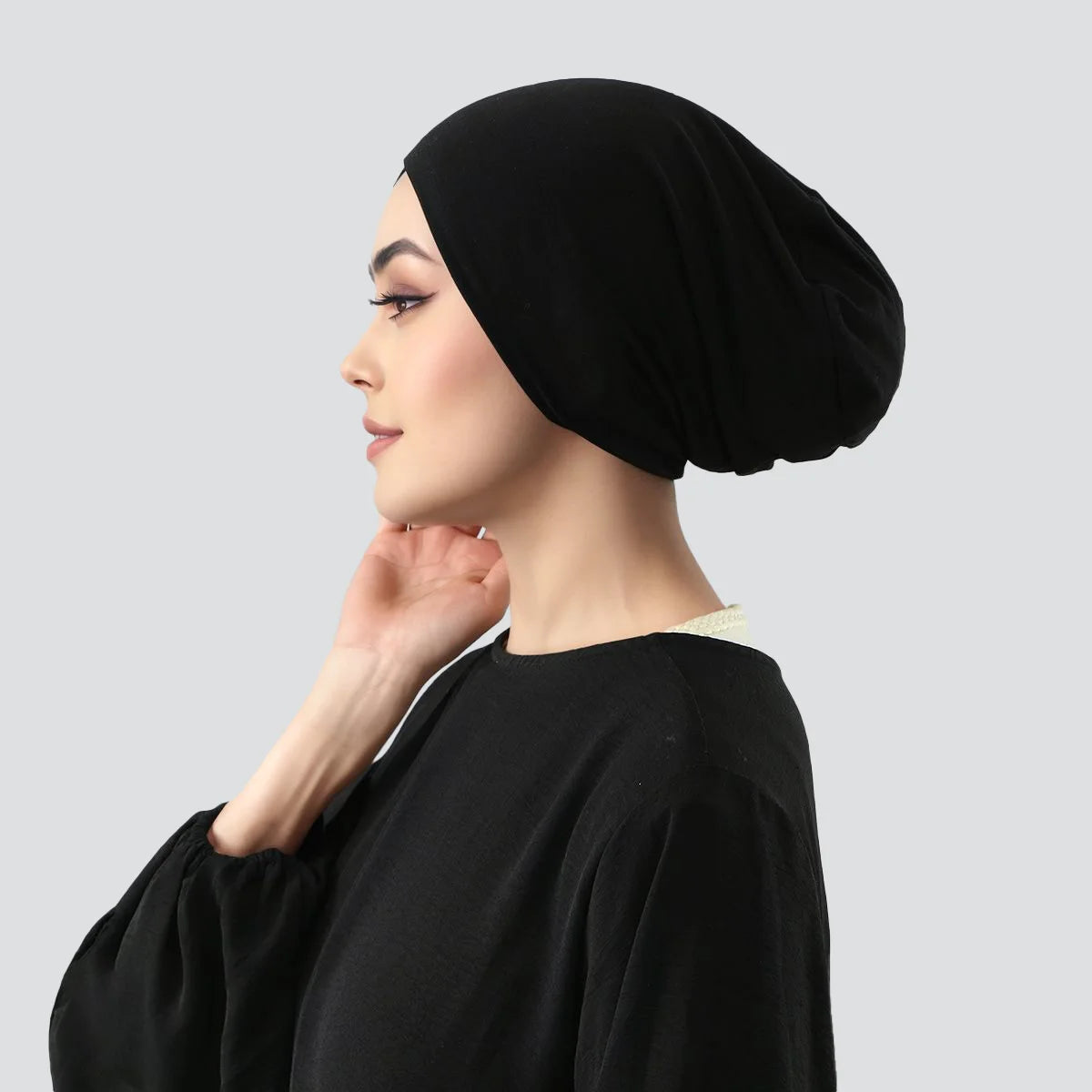 Frau im Profil mit schwarzem Stretch-Jersey-Inner-Hijab-Cap und schwarzem Oberteil.