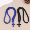 Un rosario de oración artesanal con cuerda, en azul y negro, exhibido sobre un fondo claro.