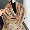Beige und schwarz gemusterter Viskoschal über einem schwarzen Top mit orangefarbenen Akzenten.