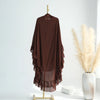 A dark brown ruffled two-layer chiffon hijab displayed on a hanger next to dried beige pampas grass.
