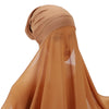 Primer plano de un hiyab y chal de chifón instantáneo beige puestos en la cabeza.