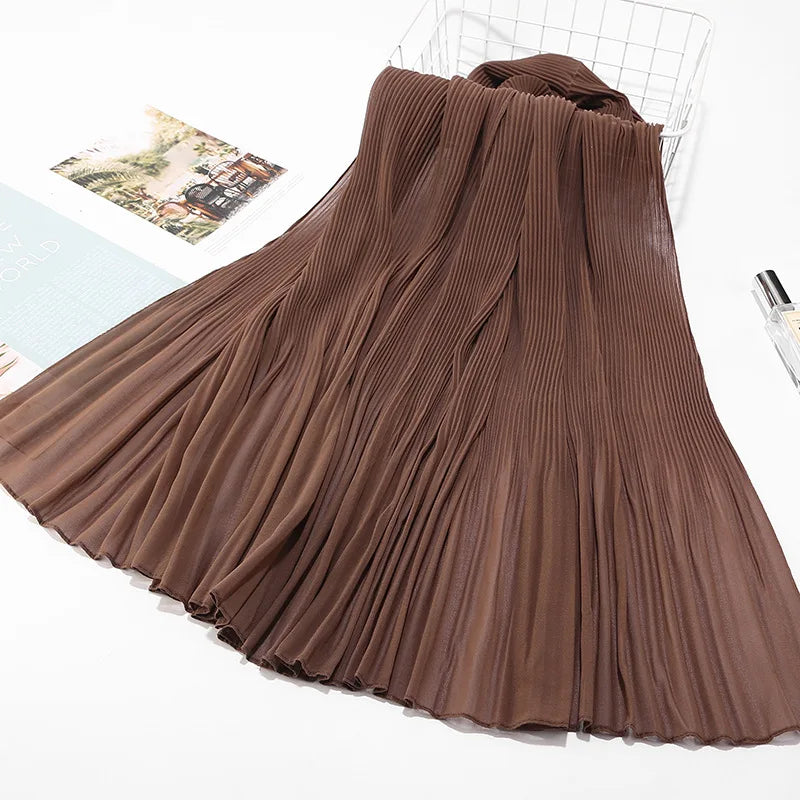 Ein drapierter brauner Crinkle-Chiffon-Hijab-Schal auf einer weißen Oberfläche.