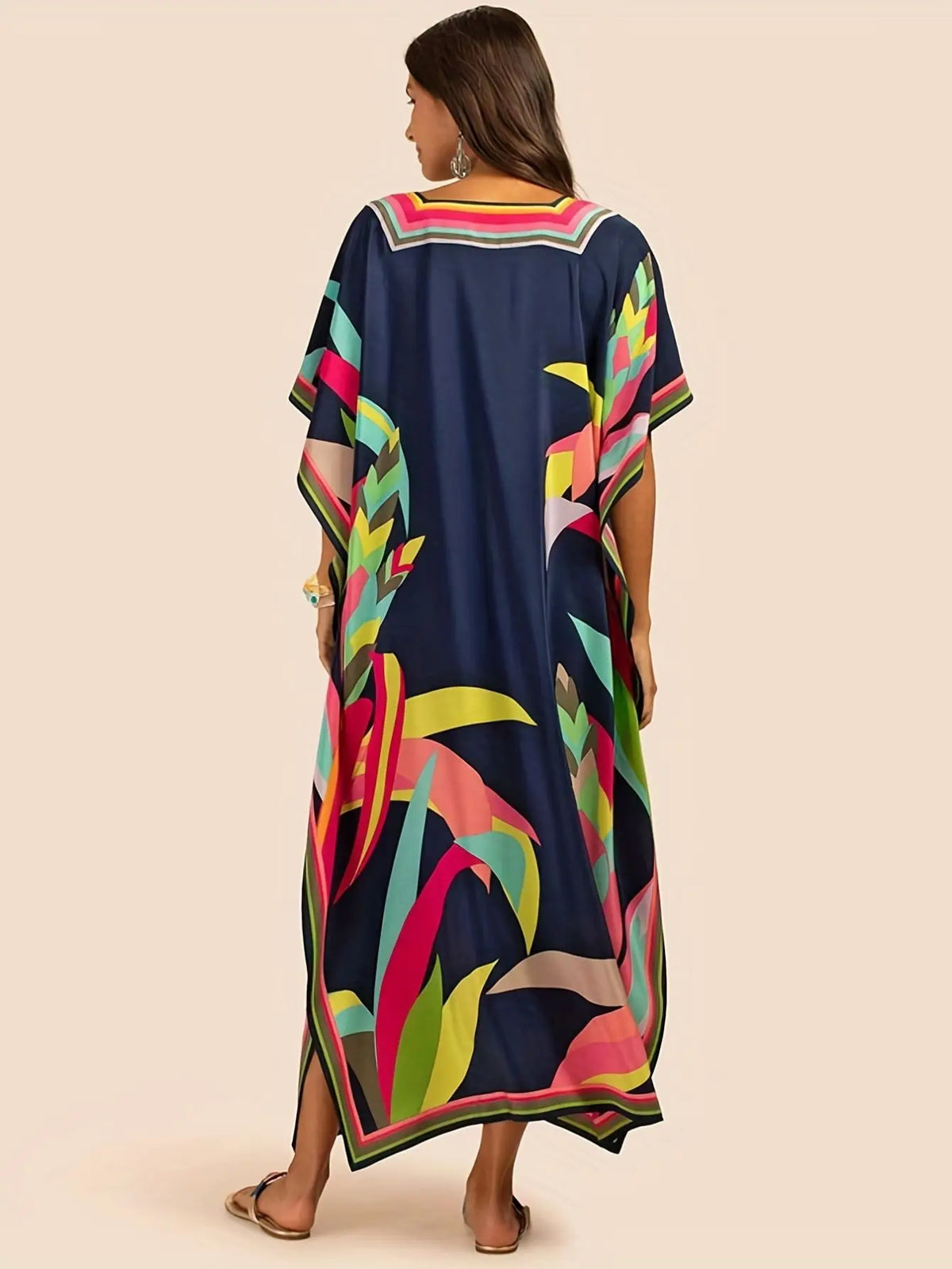 Eine Frau modelliert ein marineblaues marokkanisches Batwing Kaftan-Überkleid mit leuchtend pinken, grünen und gelben Blumenm