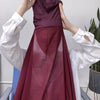 Una modelo lleva un hiyab y chal de gasa color granate oscuro con mangas blancas contra un fondo claro.