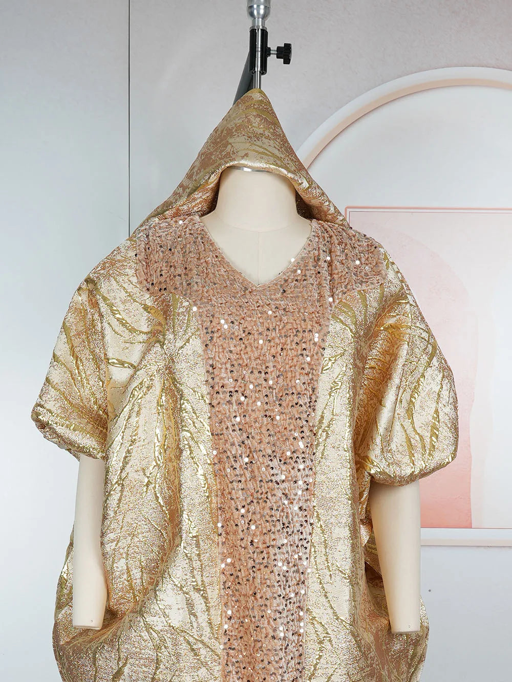 Modelo vistiendo un vestido maxi dashiki de lentejuelas doradas con una pañuelo a juego, mostrado contra un fondo claro.