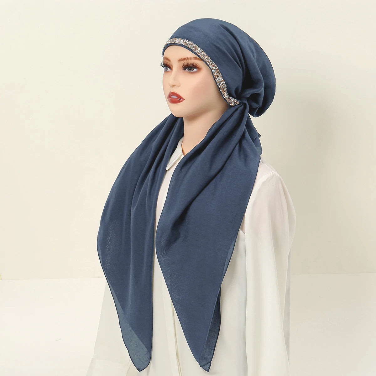 Una mujer usando una diadema elástica de diamantes azul marino para hijab, combinada con una blusa blanca.