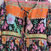 Buntes Boho-Blumendress mit Patchwork-Muster aus rosa, orange und grünen Blumen auf schwarzem Hintergrund.