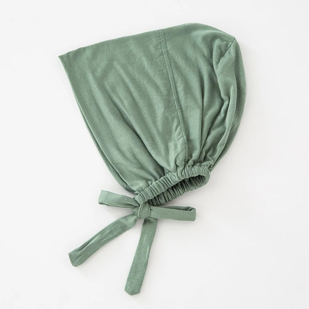 Weiches salbeigrünes inneres Hijab-Bonnet, gefaltet und mit einem Stoffband zusammengebunden.