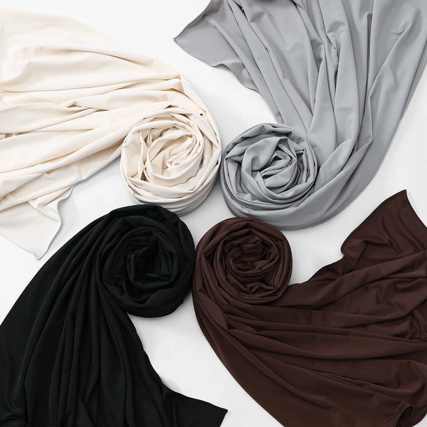 A collection of draped liquid jersey shawl hijabs in shades of beige, gray, black, and brown.