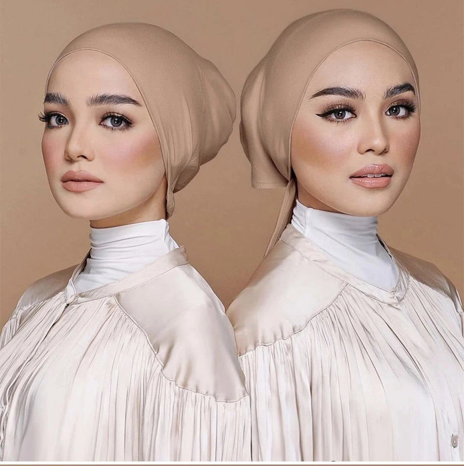Una mujer modela un elegante turbante de hijab modal beige con una blusa de cuello alto.