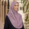 Eine Frau mit mauvem Hijab und schwarzer Kleidung in einer Außenumgebung.