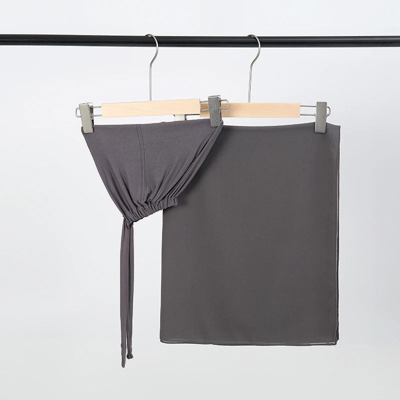 Dunkelgrauer Chiffon-Hijab und Untercap-Set an einem schwarzen Stäbchen aufgehängt.