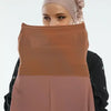 Une femme portant un hijab en mousseline beige et un haut marron, regardant l'appareil photo.