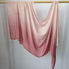 Pañuelo de hijab de algodón rayón degradado rosa pálido, drapeado sobre una varilla dorada.