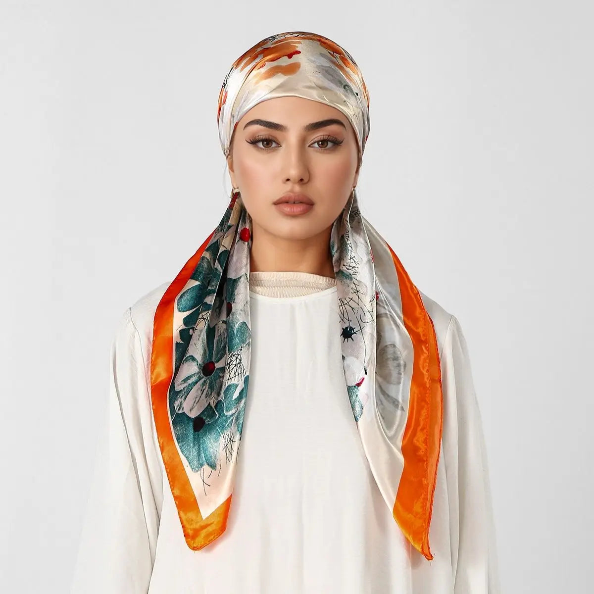 Eine Frau modelliert einen orange-weißen Seiden-Instant-Hijab-Schal, der um ihren Hals drapiert ist.