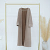A beige women's abaya trench coat displayed on a gold hanger against a white background.