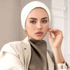 Une femme portant une tenue beige et un hijab blanc instantané, regardant directement l'appareil photo.
