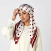 Eine Frau trägt einen weißen Seiden-Turban-Hijab mit roten Polka Dots um ihren Kopf.