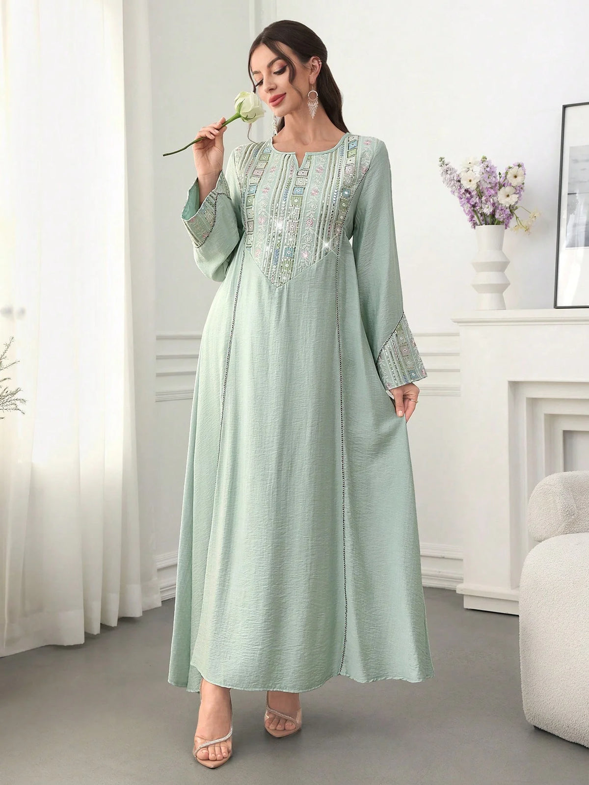 Eine Frau in einer hellgrünen Paillettenverzierte Abaya für halbformelle Anlässe.