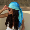 A woman wearing a bright blue silk scarf tied around her head and neck.