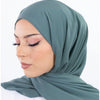 Une femme portant un hijab de mousseline teal uni, vue de profil.