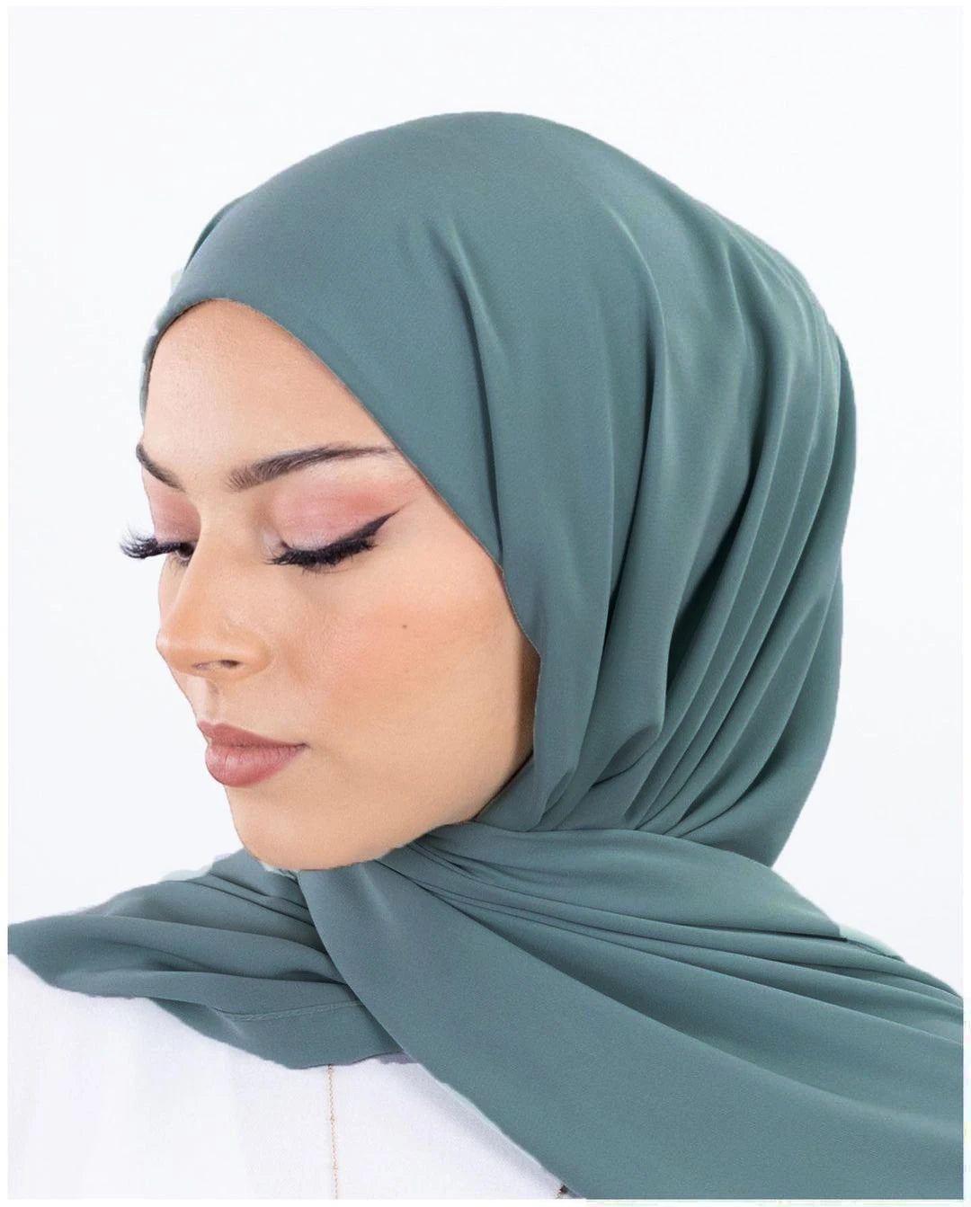 Une femme portant un hijab de mousseline teal uni, vue de profil.