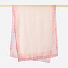 A sheer pink printed linen hijab scarf draped over a hanger.