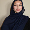 Eine Frau trägt einen marineblauen Gradient-Seide-Hijab und schwarze Kleidung.
