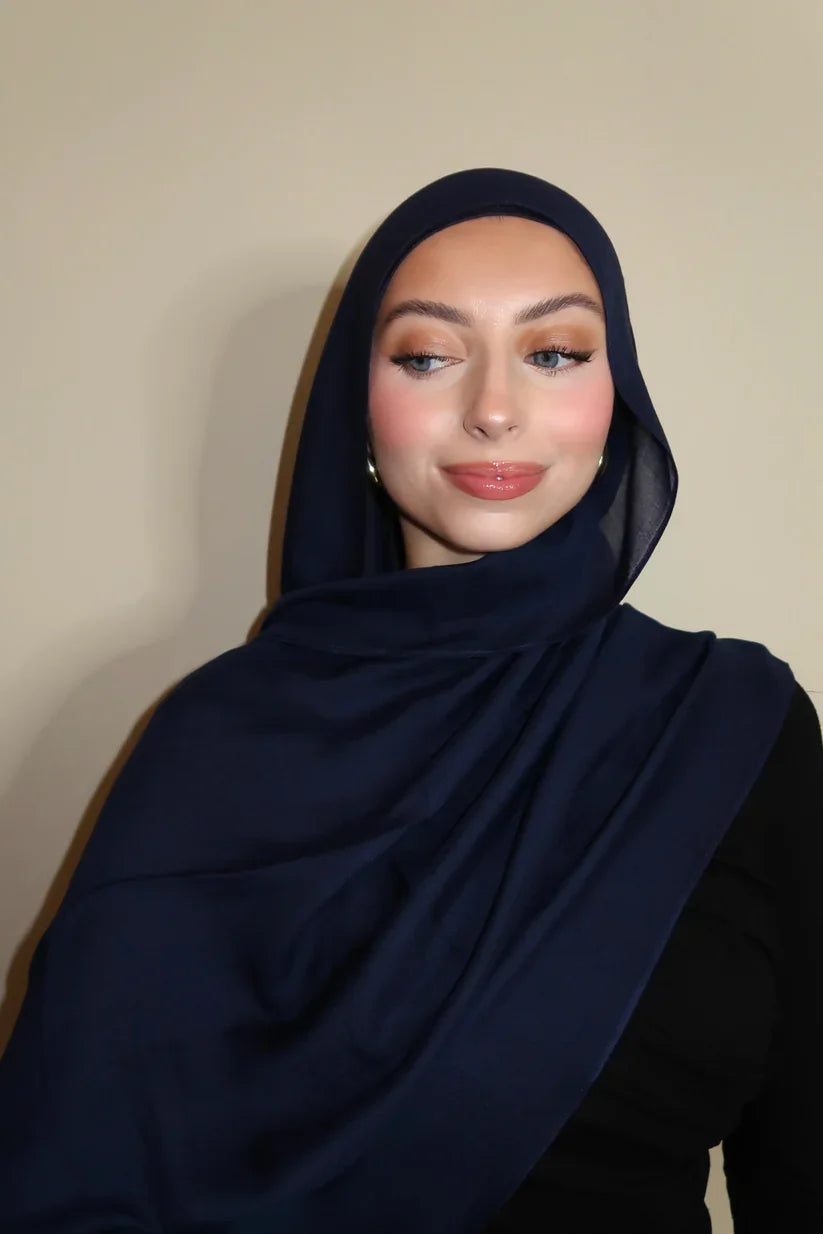 Eine Frau trägt einen marineblauen Gradient-Seide-Hijab und schwarze Kleidung.