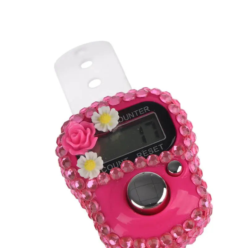A pink finger counter with a rose design and a white clip, used for meditation and counting.