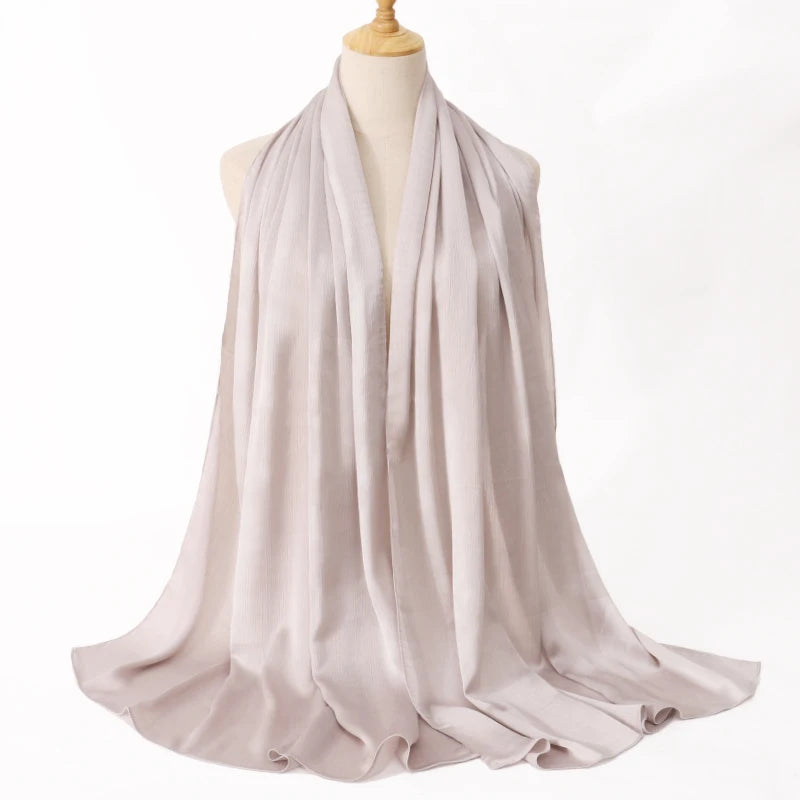 Helles beige Satin-Krinkle-Hijab-Schal, um den Hals eines Mannequins gewickelt.