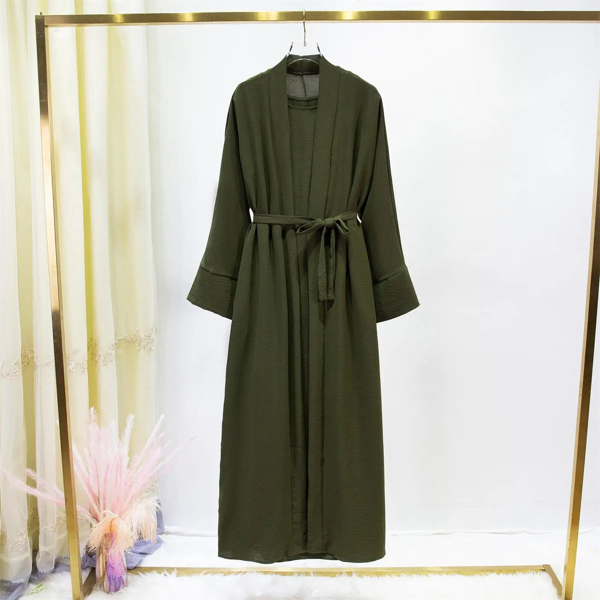 Jilbab de dos piezas color verde oliva oscuro para mujer exhibido en percha sobre fondo blanco.