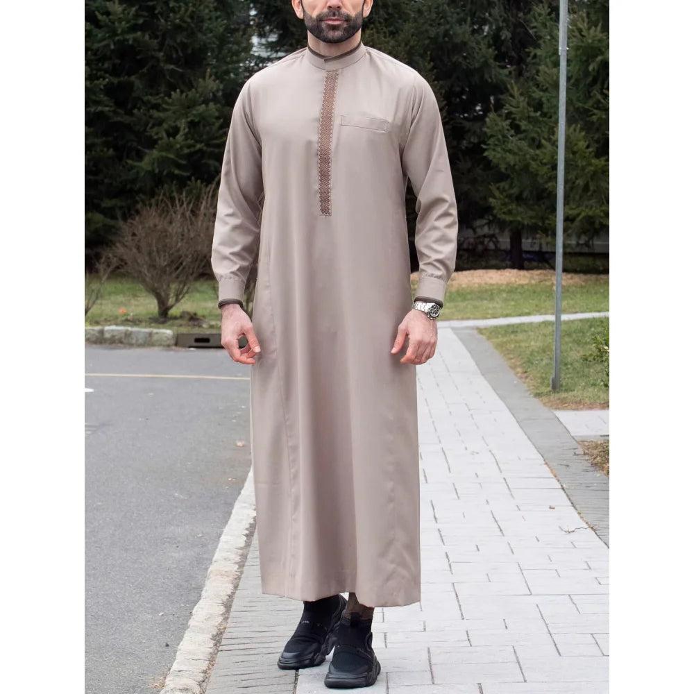 Un hombre vistiendo una jubba thobe islámica tradicional beige con cuello mandarín y detalles de costura visibles.