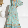 A woman wearing a light blue floral print maxi dress with lantern sleeves and embroidery.
