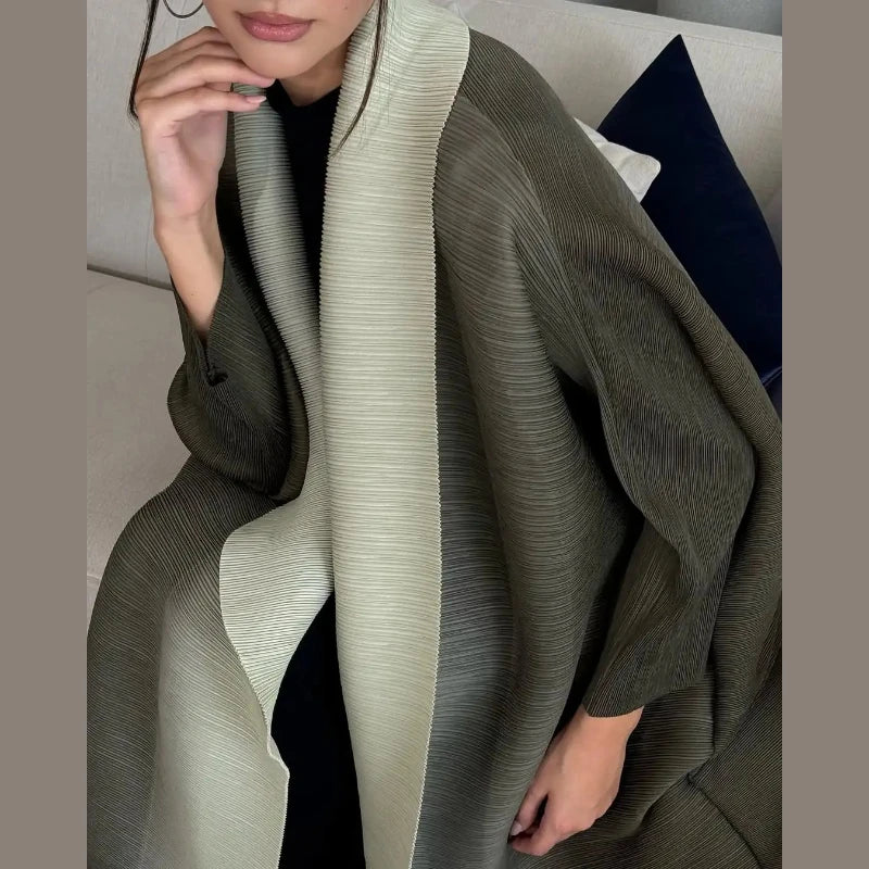Eine Frau trägt einen fließenden, plissierten Abaya-Cardigan in olivgrünen und cremigen Tönen.