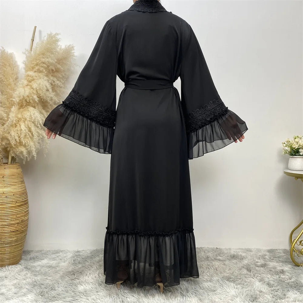 Schwarze, bodenlange Abaya mit durchscheinender Spitze und langen Ärmeln vor weißem Hintergrund.