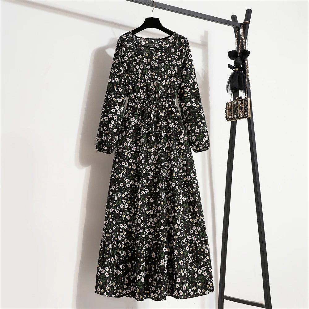 Schwarzes Maxi-Kleid mit weißem Blumenmuster an einem schwarzen Kleiderständer.