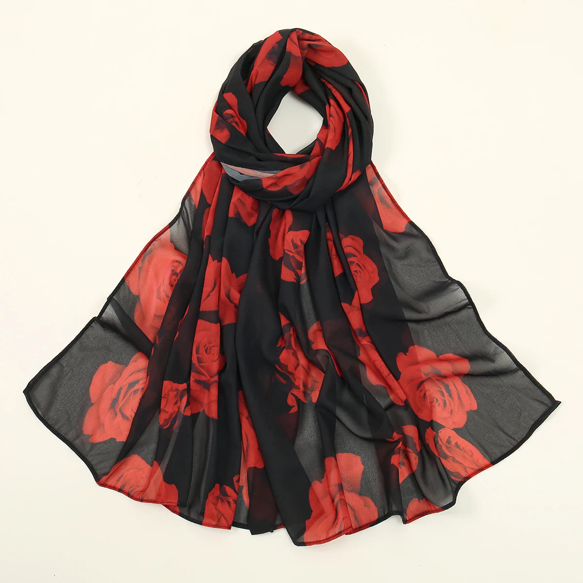 Una bufanda de gasa negra con estampado floral rojo atada en un nudo y drapeada alrededor del cuello.