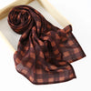 Un foulard cachemire à carreaux brun foncé drapé sur un cadre en bois.