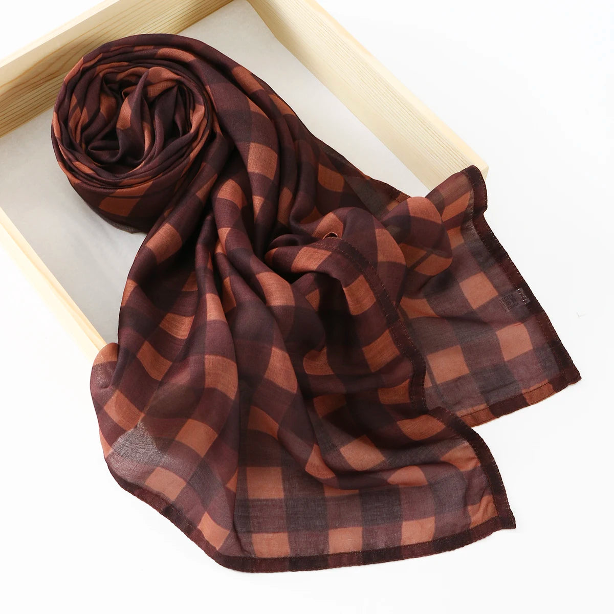 Un foulard cachemire à carreaux brun foncé drapé sur un cadre en bois.