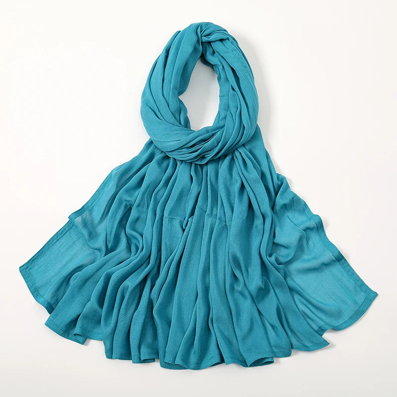 Ein gedecktes tealblaues Viscose-Hijab, elegant um den Hals und die Schultern drapiert.